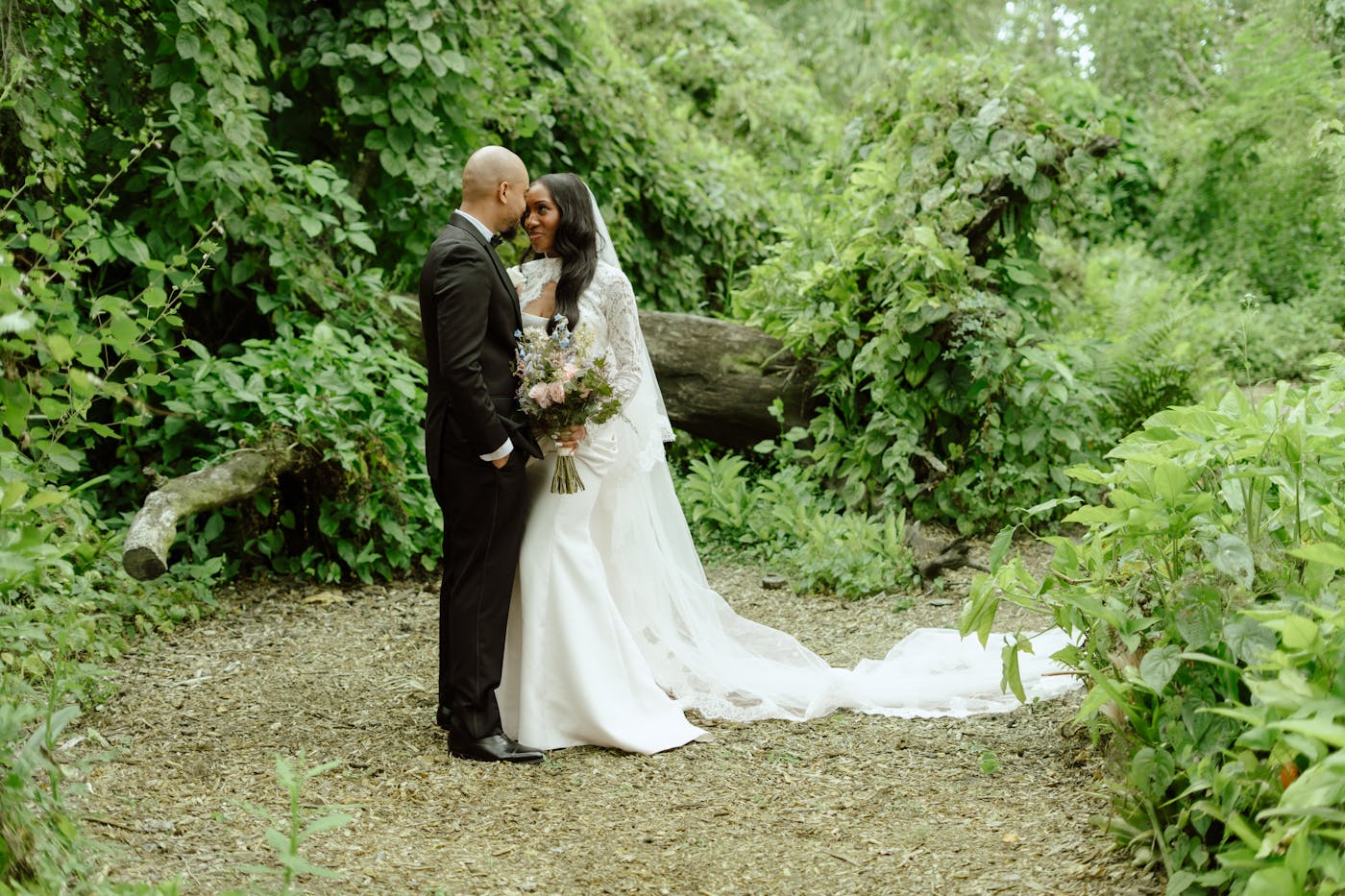 Bride and groom standing together in a lush outdoor wedding setting